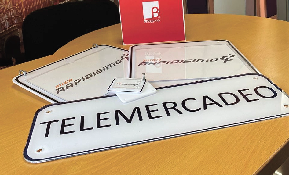 Placas de señalización corporativa en acrílico con impresión de marca para Inter Rapidísimo, incluyendo placa de 'Telemercadeo' con acabados profesionales y dilatadores, fabricadas por Bresspop.