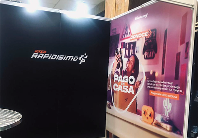 Stand publicitario impreso a gran formato por Bresspop, con banners de Inter Rapidísimo y publicidad de 'Pago en Casa' con alta resolución y fidelidad de color.