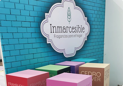 Montaje publicitario de Bresspop con vinilo adhesivo decorativo tipo ladrillo azul, logo corporativo de 'Inmarcesible' y cubos promocionales impresos a gran formato.